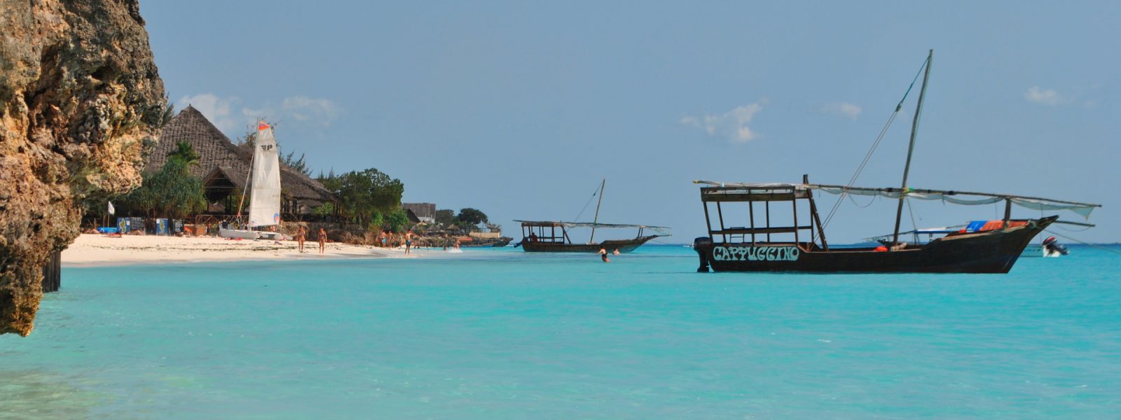 Dhow boat off a white-sand beach on a Zanzibar spice tour